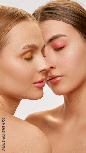 Love. Couple of beautiful sensual young women, blond and brunette with well-kept skin posing over light background. Concept of natural beauty, fashion, skin care and health