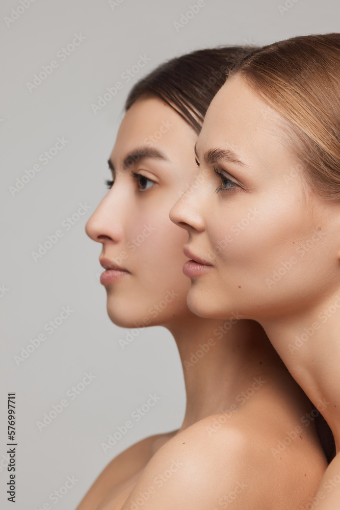 Profile view of beautiful elegant young women, blond and brunette with well-kept skin posing over light background. Concept of natural beauty, fashion, skin care and health Profile view of beautiful elegant young women, blond and brunette with well-kept skin posing over light background. Concept of natural beauty, fashion, skin care and health