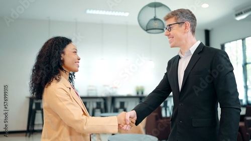 Businessman caucasian shake hand of African American woman partner client making deal, hiring or thanking for collaboration at diverse business