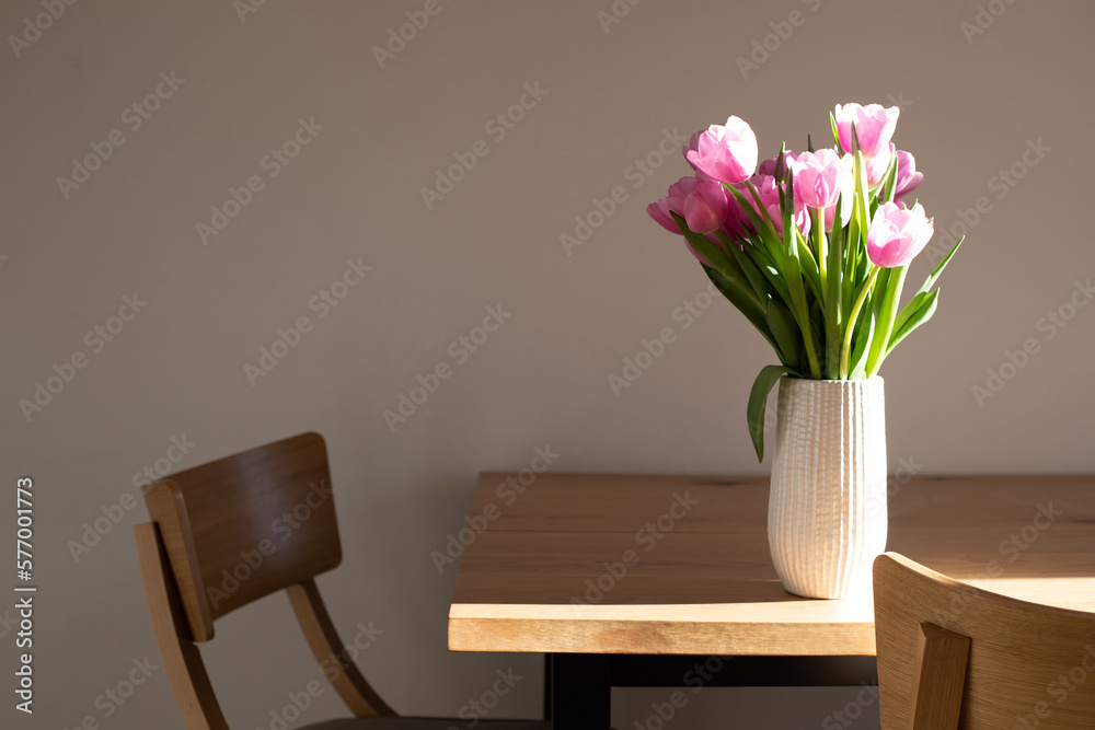 Gently pink bouquet of tulips in a white vase on wooden table. Spring background with a bouquet of flowers. Front view Gently pink bouquet of tulips in a white vase on wooden table. Spring background with a bouquet of flowers. Front view