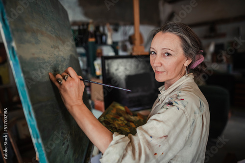 Portrait of a woman painting a picture while looking at the camera