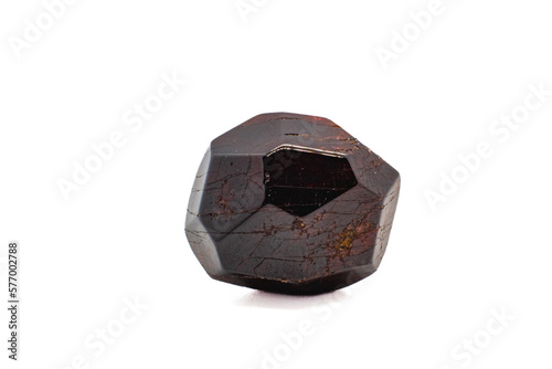 Dodecahedral natural deep red garnet lightly tumbled polished crystal isolated on a white surface background macro photography