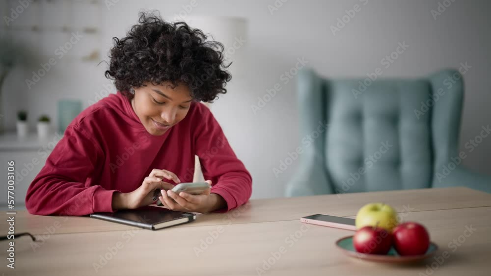 Young african american woman at home smiling doing business correspondence with client and successful freelancing deal or chatting friends text message. Girl use mobile phone for online communication. Young african american woman at home smiling doing business correspondence with client and successful freelancing deal or chatting friends text message. Girl use mobile phone for online communication.