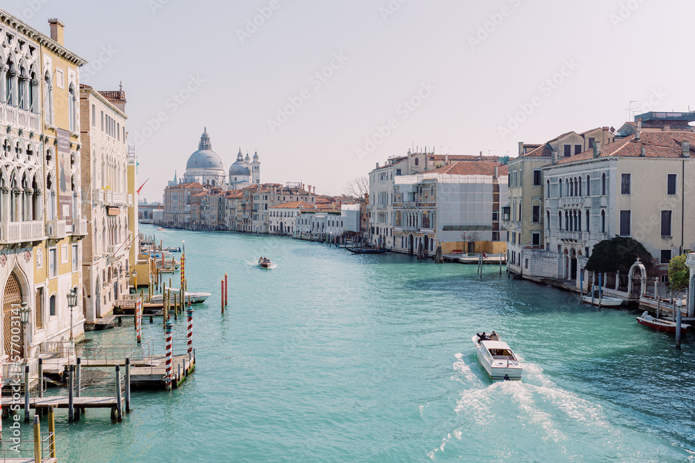 A motorboat cruises a river in Venice, with the city in the background. Sun, blue sky, turquoise water: You want to go on vacation immediately!