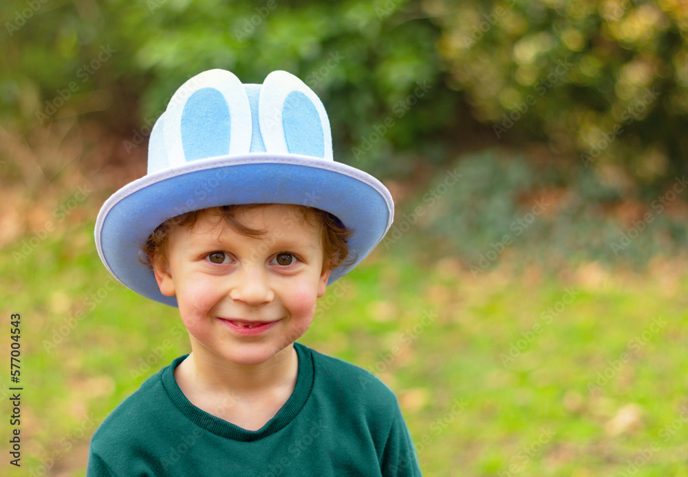smiling child boy in blue hat with rabbit ears in garden. Easter bunny funny costume smiling child boy in blue hat with rabbit ears in garden. Easter bunny funny costume