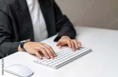 Female hands typing on wireless computer keyboard.