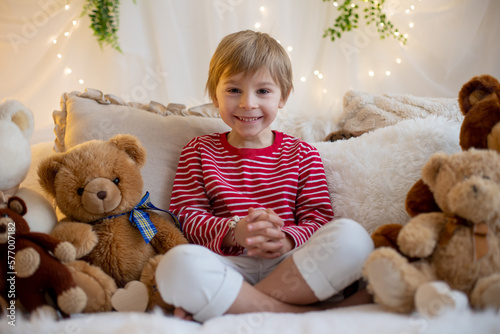 Cute preschool boy, playing with white and red bracelets. Martenitsa, white and red strains of yarn, Bulgarian folklore tradition, welcoming spring in March, adornment symbol