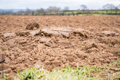 Topsoil brown soil on an agricultural field view from low angle, focus on foreground during cloudy day