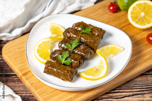 Olive oil leaf wrap. Turkish cuisine delicacies. Wrapping grape leaves on wood background. Local name zeytinyaglı yaprak sarma or dolma photo