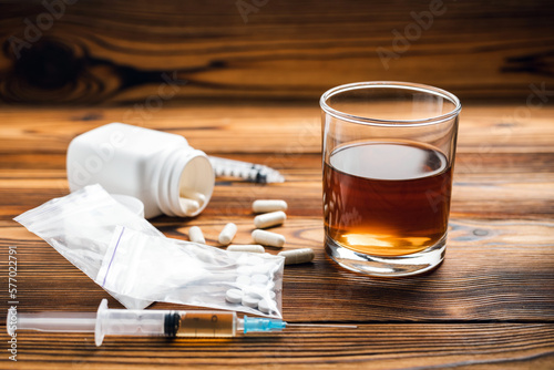 Canvastavla Glass with alcohol drink, whisky or brandy, white pills, syringe with a drugs dose, narcotic in transparent bag on a wooden table