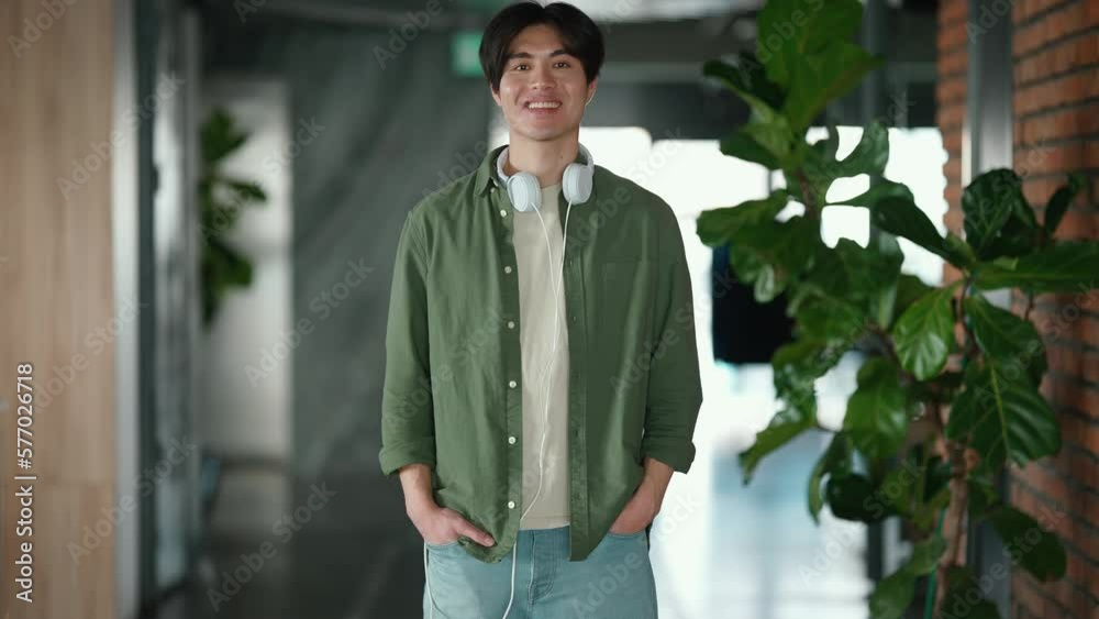 Friendly brunet Asian man looking at the camera while standing in the office Friendly brunet Asian man looking at the camera while standing in the office