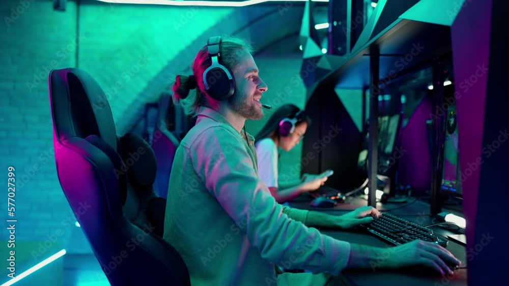 Laughing man gamer plays RPG video game on a championship. Stylish Neon Cyber Games Laughing man gamer plays RPG video game on a championship. Stylish Neon Cyber Games