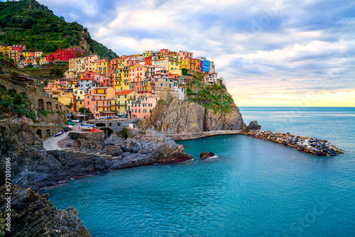 Fototapete Stunning view of Manarola village in Cinque Terre National Park, beautiful cityscape with colorful houses and green terraces on cliffs over a sea, Liguria region of Italy