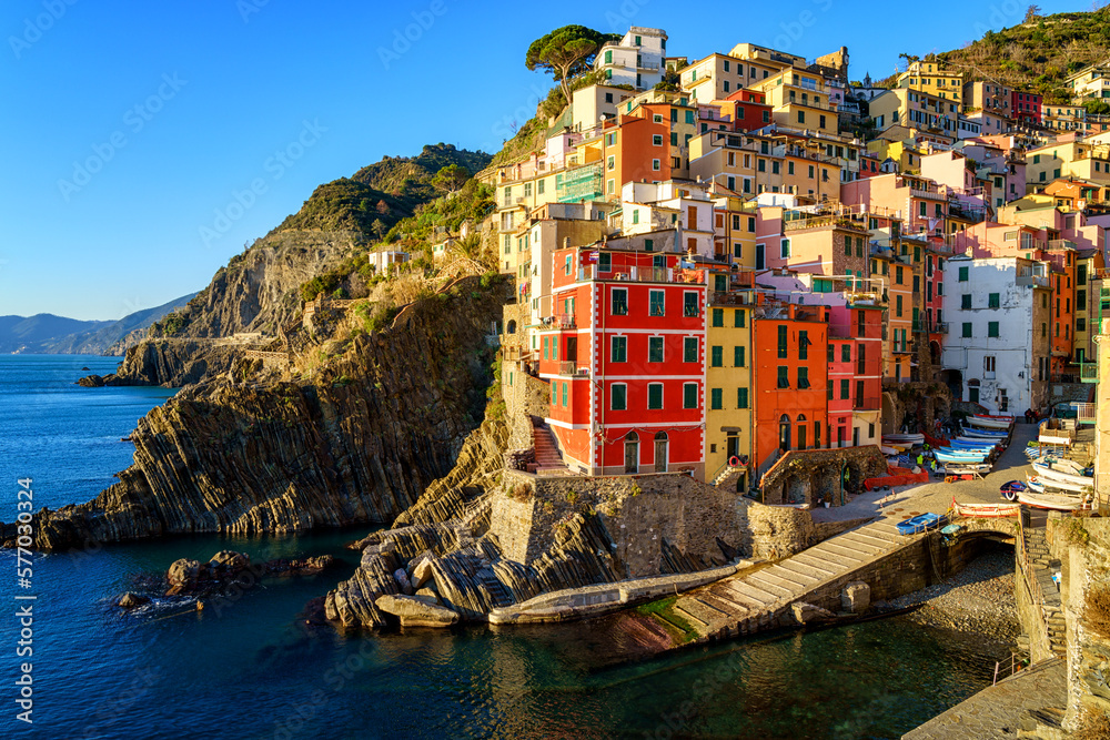 Stunning view of Riomaggiore village in Cinque Terre National Park, beautiful cityscape with colorful houses and green terraces on cliffs over a sea, Liguria region of Italy. Outdoor travel background