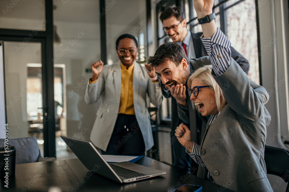 Obraz premium Shot of diverse business people working together on laptop. Creative female and male executives celebrating great business news.