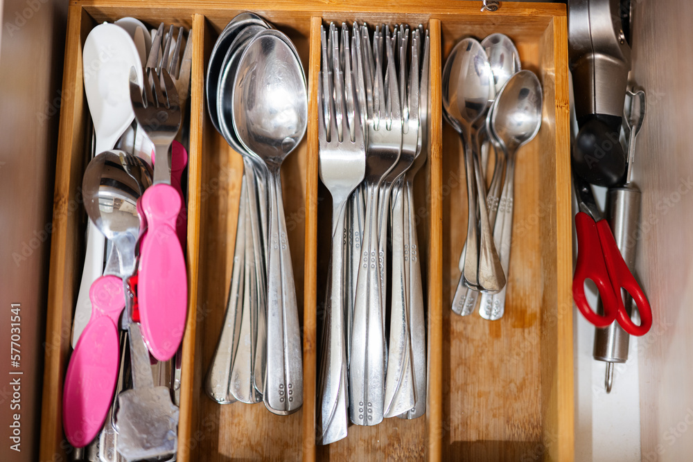 Clean and silver spoons, forks at kitchen drawer with cutlery set. Flat lay view of organizer tray with simple kit of utensils in open storage box. Clean and silver spoons, forks at kitchen drawer with cutlery set. Flat lay view of organizer tray with simple kit of utensils in open storage box.