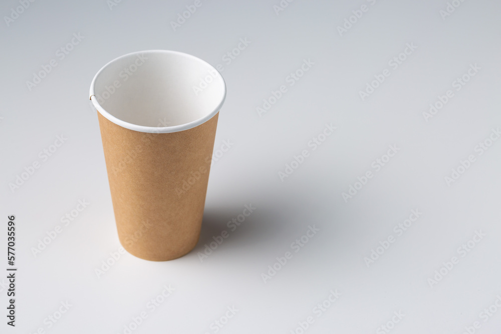 Disposable cardboard biodegradable glass on a white table, gray background. Disposable cardboard biodegradable glass on a white table, gray background.