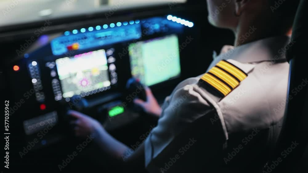 Back view of young, female pilot standing in cabin of airplane, sitting. Woman wearing uniform, holding, turning, taking wheel, looking. Concept of traveling by aviation. Back view of young, female pilot standing in cabin of airplane, sitting. Woman wearing uniform, holding, turning, taking wheel, looking. Concept of traveling by aviation.