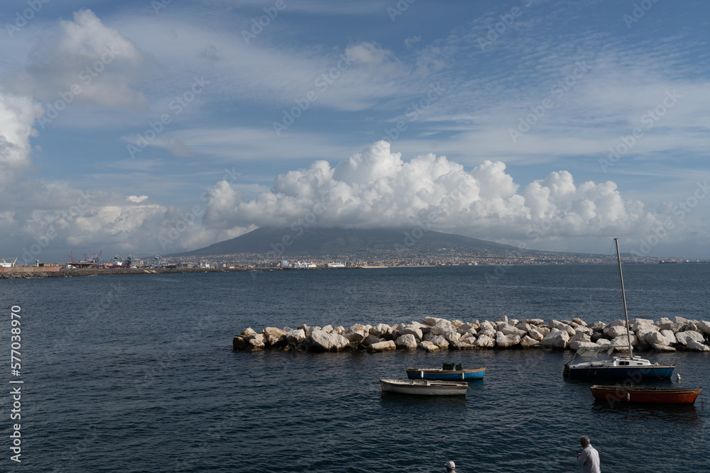 Local fishing boats at a small port and Vesuvius volcano in the background