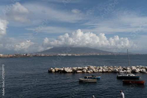 Local fishing boats at a small port and Vesuvius volcano in the background