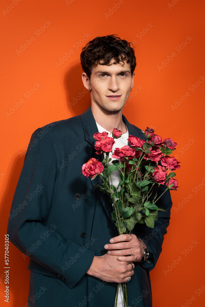 Portrait of smiling man in blue jacket holding roses on red background. Portrait of smiling man in blue jacket holding roses on red background.