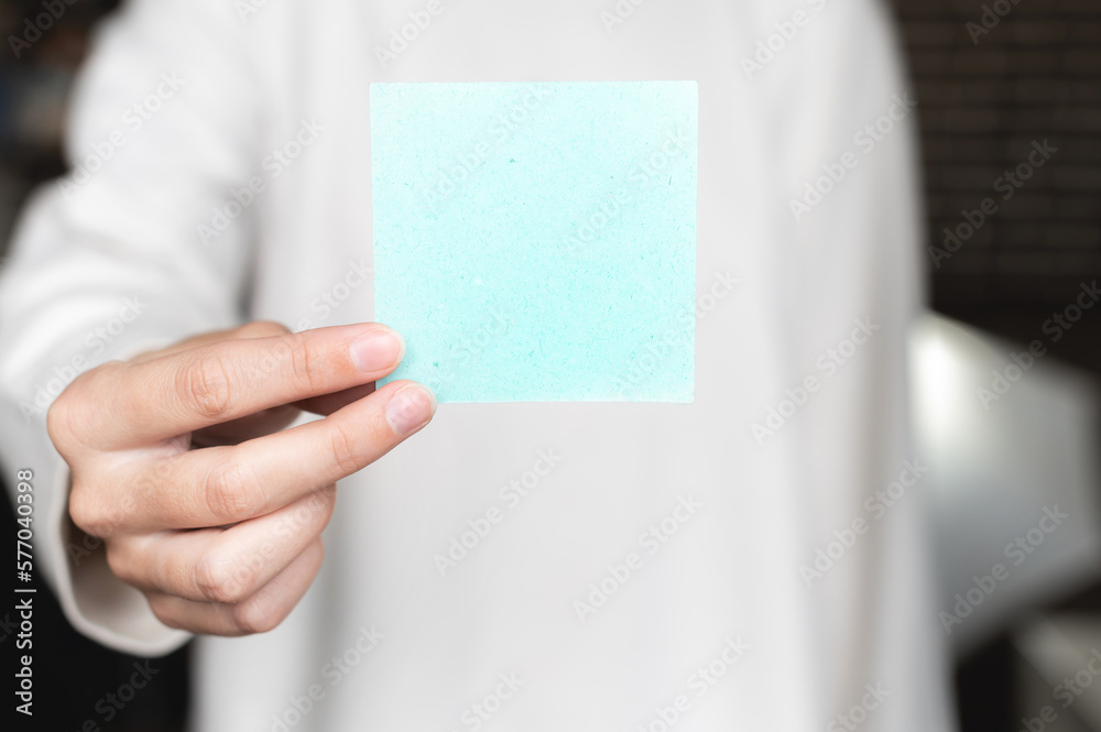 woman is holding a note with blank space. A woman is holding a square empty blank sticker in her hands. Close up background space for text woman is holding a note with blank space. A woman is holding a square empty blank sticker in her hands. Close up background space for text