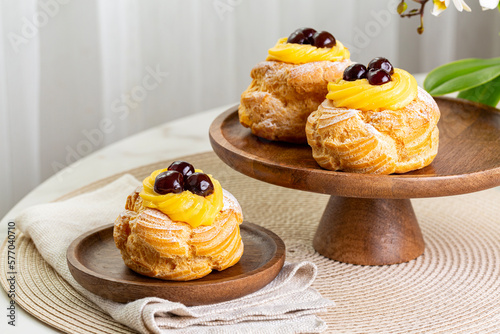 Table with Italian pastry - zeppole di San Giuseppe - baked puffs made from choux pastry, filled and decorated with custard cream and cherry.  Saint Joseph's Day. photo