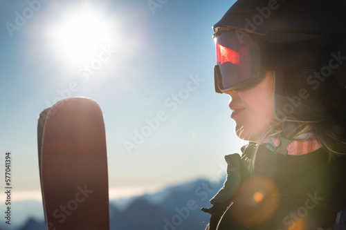 Close-up, ski goggles and a woman's face in a ski resort against the backdrop of mountains and sky on a sunny day
