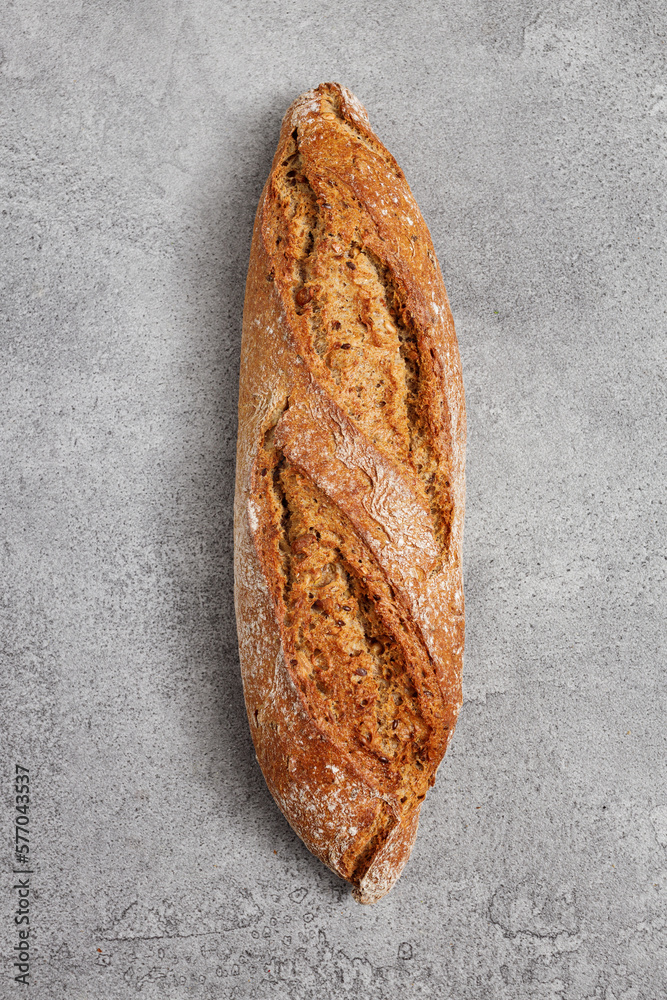 Rustic sourdough rye baguette with cereal on a gray table, top view Rustic sourdough rye baguette with cereal on a gray table, top view