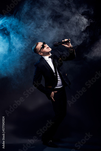 Full length of man who singing in microphone on dark smoke background, actor, singer, host of event