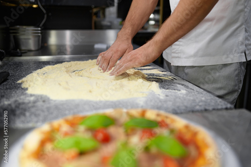 Closeup chef hands mixing flour for kneading pizza dough