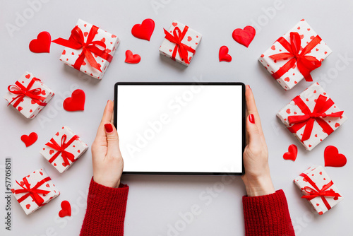 Female hands using a laptop for Valentine day background, gift box and envelope, hearts