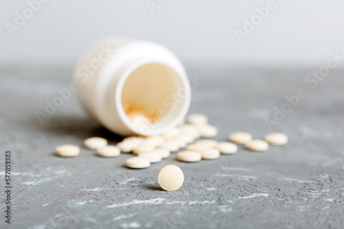 Medicine bottle and white pills spilled on a light background. Medicines and prescription pills flat lay background. White medical pills and tablets spilling out of a drug bottle