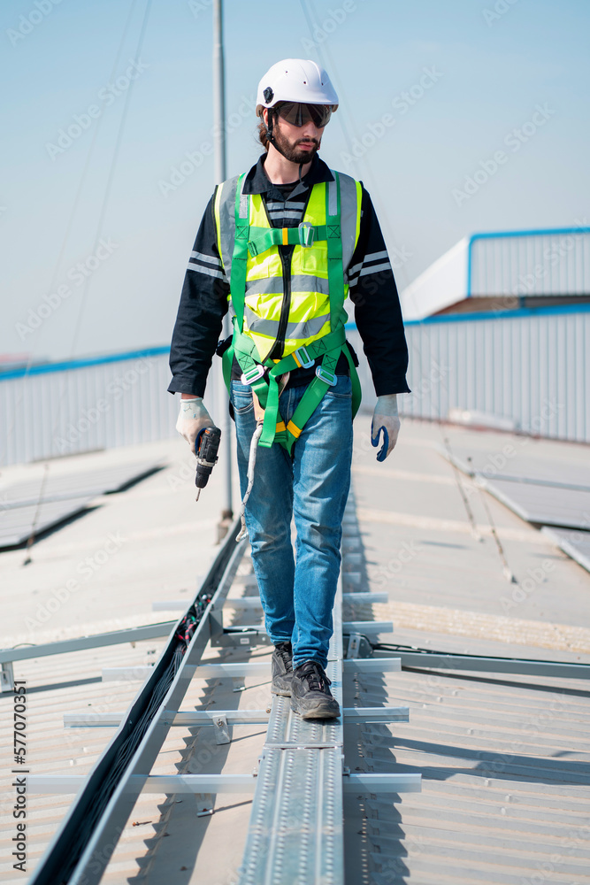 Technician with drill installing solar panels on rooftop Technician with drill installing solar panels on rooftop