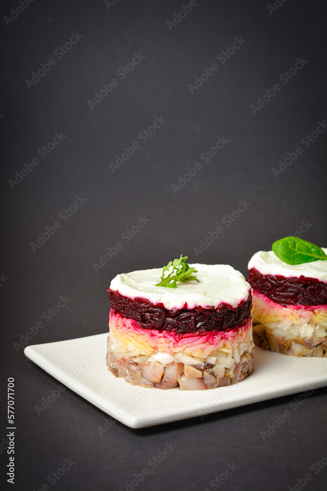 Side view of Scandinavian layered fish salad Herring under fur coat. Portion with marinated herring, onion, grated potato, beetroot, mayonnaise on top. Dark copy space background Side view of Scandinavian layered fish salad Herring under fur coat. Portion with marinated herring, onion, grated potato, beetroot, mayonnaise on top. Dark copy space background