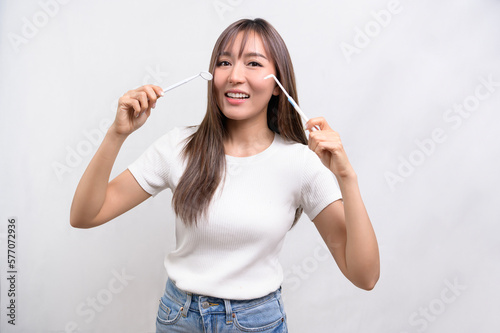 Young smiling woman holding dental equipment over white background studio, dental healthcare and Orthodontic concept