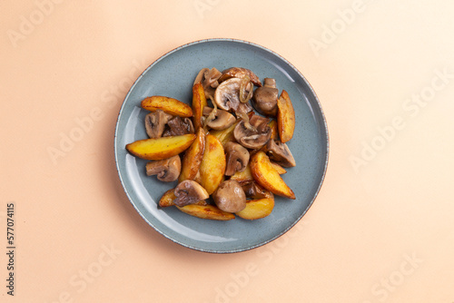 Fried potatoes with mushrooms on a light background.