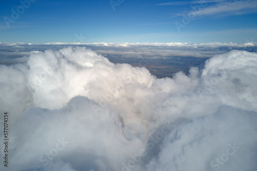 Aerial view from airplane window at high altitude of earth covered with white puffy cumulus clouds