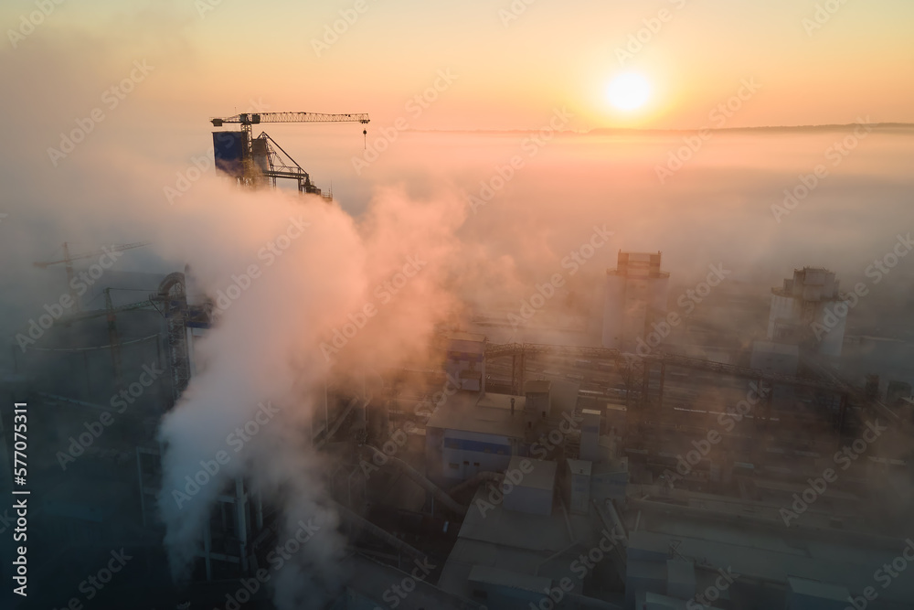 Aerial view of cement factory with high concrete plant structure and tower crane at industrial manufacturing site on foggy evening. Production and global industry concept Aerial view of cement factory with high concrete plant structure and tower crane at industrial manufacturing site on foggy evening. Production and global industry concept