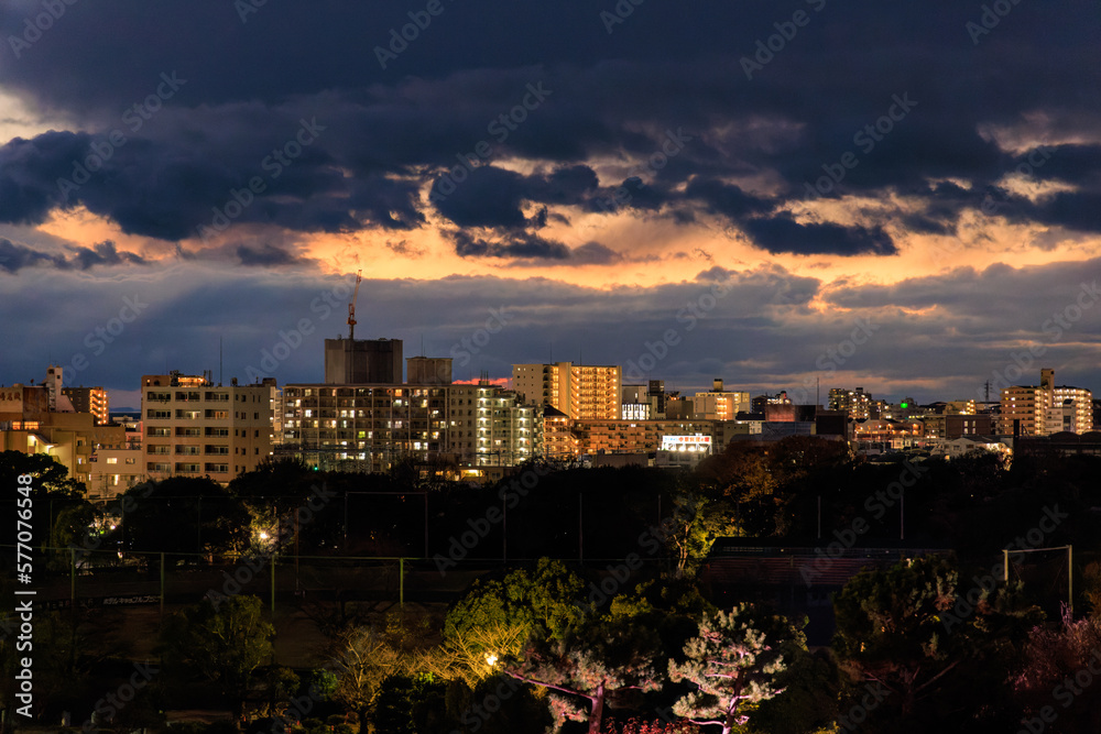 Obraz premium Dramatic clouds after sunset over low rise buildings by park
