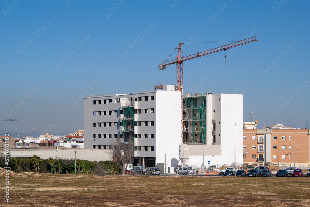 Obraz premium Edificio en construcción con grúa en un día soleado.