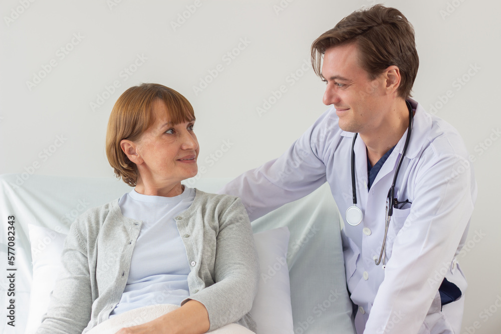 the doctor is examining the patient in the hospital. Caucasian doctor wearing gown and listening device and a female patient looking at each other at the hospital. the doctor is examining the patient in the hospital. Caucasian doctor wearing gown and listening device and a female patient looking at each other at the hospital.
