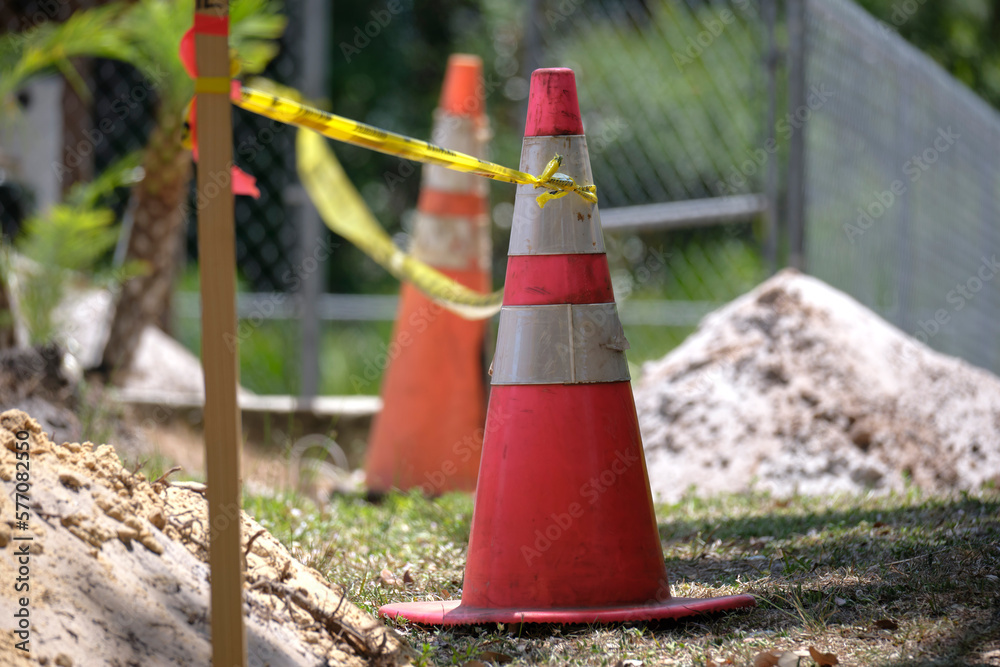Yellow warning cones and tape as protective restriction barrier at industrial construction site. Safety for pedestrians Yellow warning cones and tape as protective restriction barrier at industrial construction site. Safety for pedestrians