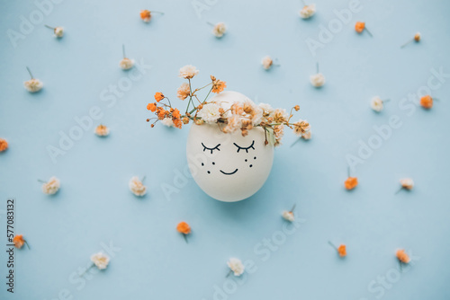Happy Easter! Decorated with spring flowers Easter egg on blue background. Stylish tender spring template with space for text. Greeting card or banner