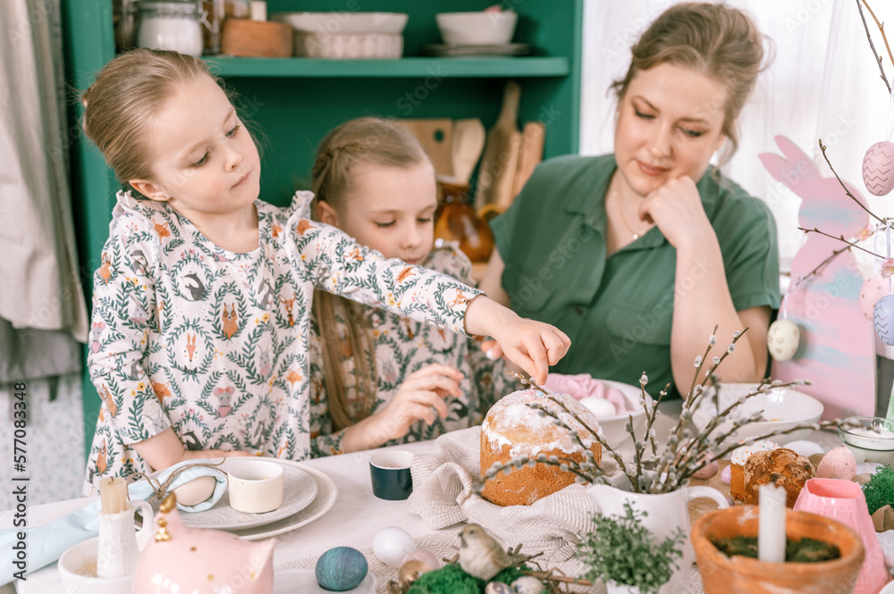 Fototapeta premium easter holiday time in spring season. happy family candid little kids sisters girls together mother have fun at home decorating table for lunch or dinner. traditional food. festive home decor