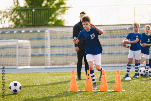 Group of school boys at soccer training session with school coach trainer. Ki...