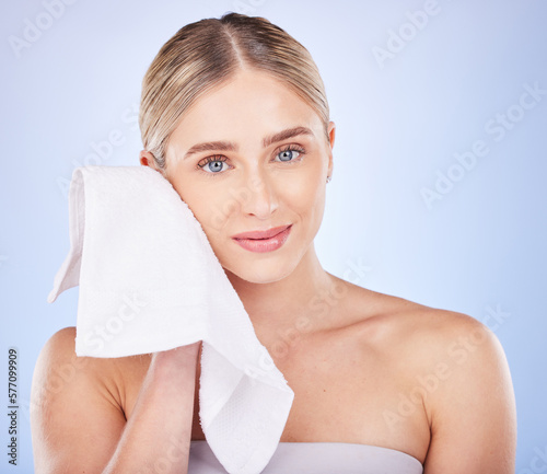 Skincare, face and woman with towel to wipe in studio isolated on a blue background. Facial portrait, makeup cosmetics and beauty of young female model with fabric cloth to dry skin after cleaning.