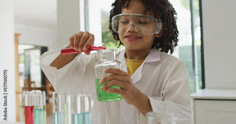 Happy biracial boy making chemistry experiments, holding test tube Happy biracial boy making chemistry experiments, holding test tube