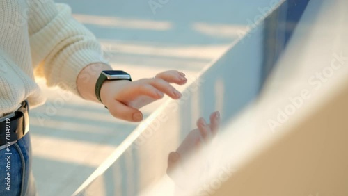 Woman using touchscreen terminal in mall. Detail view outstretched female hand touching modern big timetable or info screen in interior. Side view fingers swiping on display at out of focus background