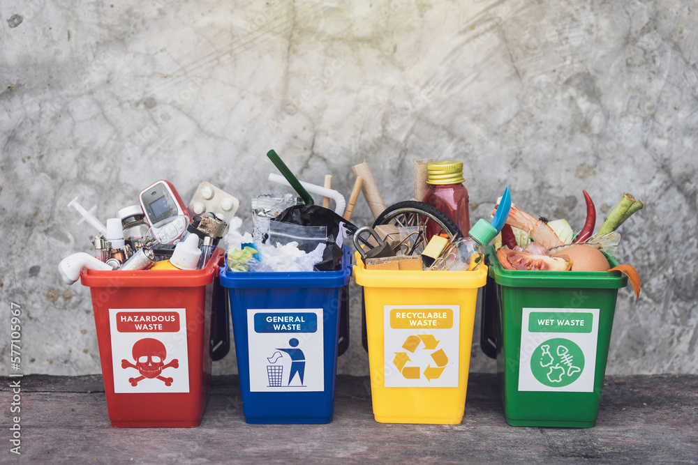 The concept of waste classification for recycling. Collection of waste bins full of different types of garbage in separation according to the color of the bin with old wall background.